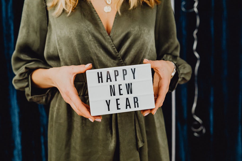 Woman holding a Happy New Year sign, ready for holiday celebration.